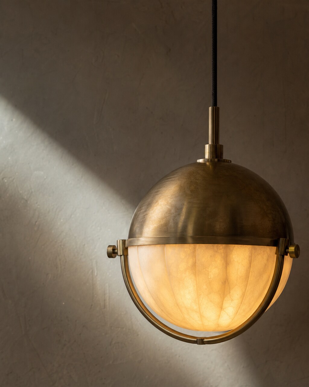 The Helios I pendant — hand-blown alabaster cradled in spun brass.